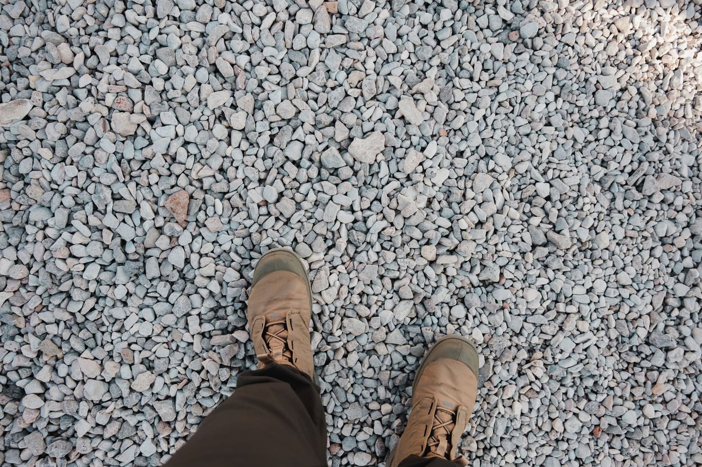 A person's boots standing on a field of crushed gravel
