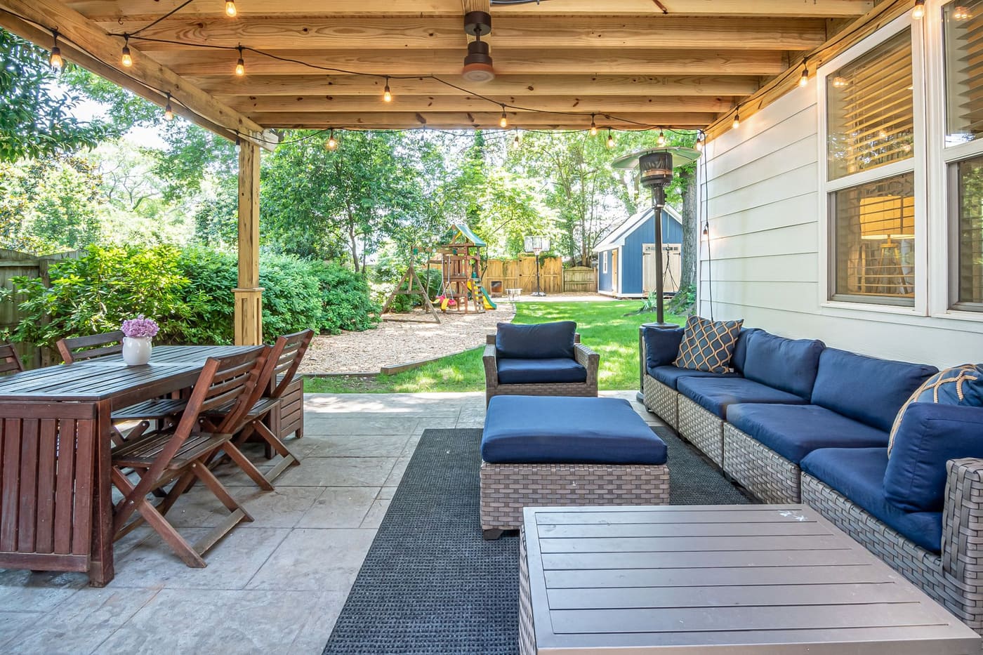 Covered patio with string lights, a dining table and a sofa with cushions