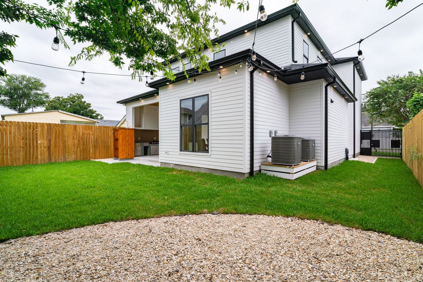 Small tidy lawn with a gravel border beside a wooden fence and a white house